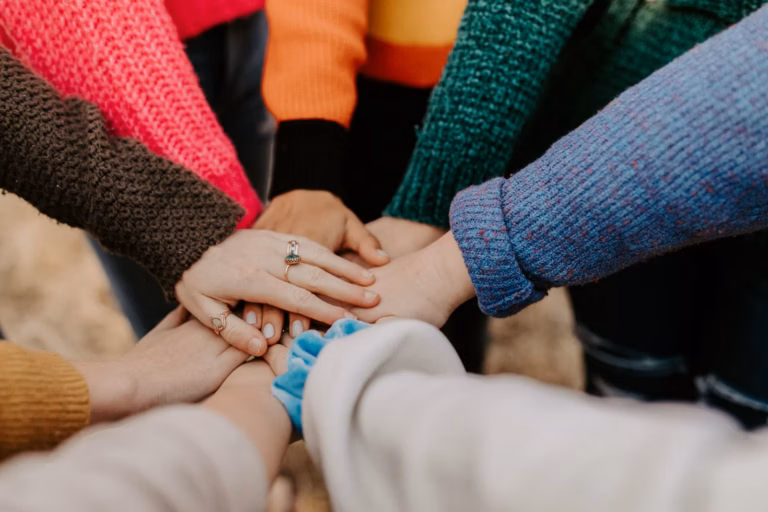 Diverse people sitting in circle holding hands at group therapy
