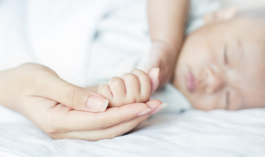 Asian parent hands holding newborn baby fingers, Close up motherâs hand holding their new born baby. Love family healthcare and medical concept