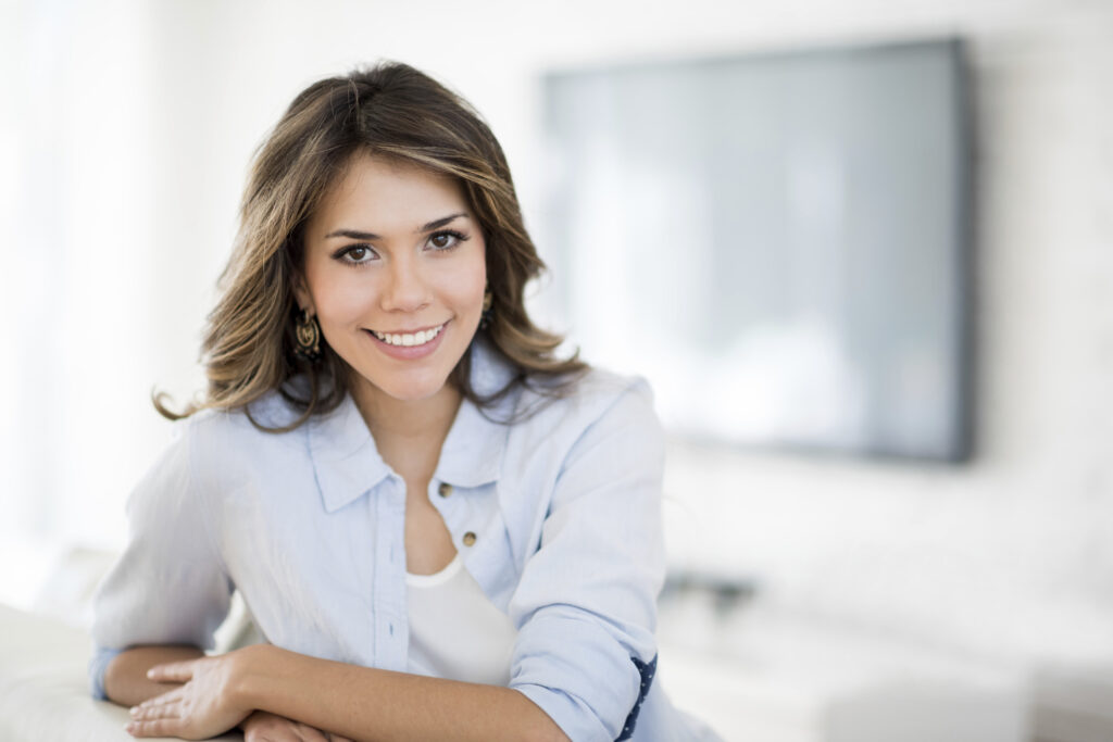 Beautiful woman at home smiling and sitting at the living room