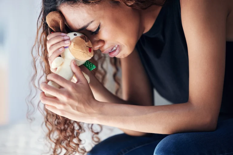 Shot of a young woman looking sad while holding a teddy bear