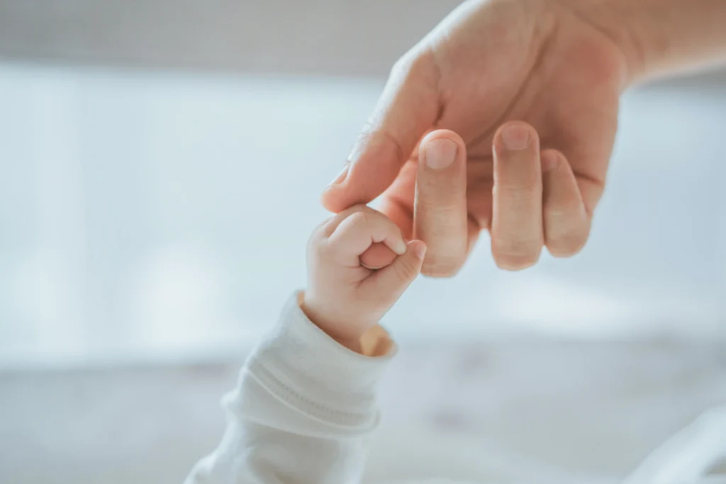 Close-up little hand of child baby holding hand of mother, A newborn holds on to mom'